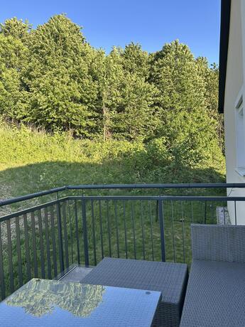 Balkon mit Loungemöbeln und Blick auf Bäume und Wiese