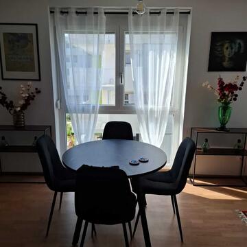 Esszimmertisch im Wohn-Essbereich, runder Tisch mit vier Sesseln dahinter ein Fenster und Bilder links und rechts neben dem Fenster