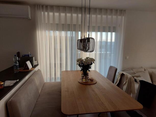 Heller Essbereich mit Eichentisch, Polsterbank und bodentiefen Fenstern mit Ausblick in einer modernen Wohnung in Eisenstadt