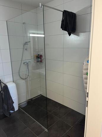 Geräumige bodenebene Dusche mit Glastrennwand, Regendusche und großformatigen Wandfliesen