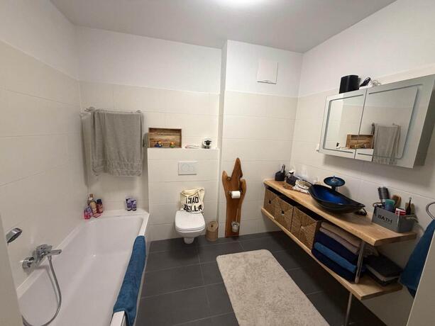 Reihenhaus Pinkafeld Badezimmer – Bad mit Badewanne, Wand-WC und Waschtisch auf Holzkonsole