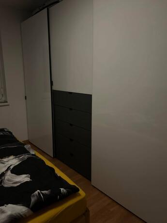 Weißer Kleiderschrank mit dunkler Kommode im Schlafzimmer