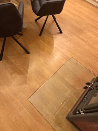 Reihenhaus Pinkafeld Detail – Funkenschutzplatte aus Glas vor dem Kaminofen auf Laminatboden